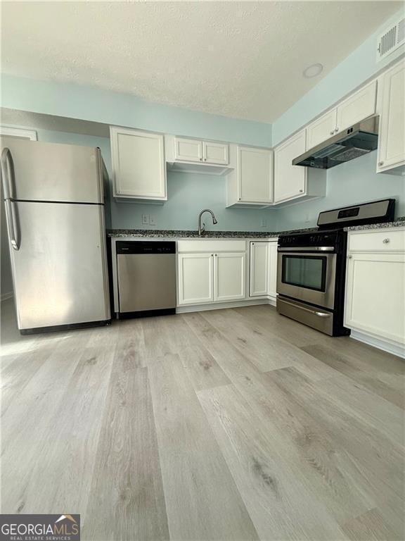 5075 Forest Downs Ln, Atlanta, GA 30349 - kitchen featuring light wood-style flooring, a textured ceiling, under cabinet range hood, visible vents, and appliances with stainless steel finishes