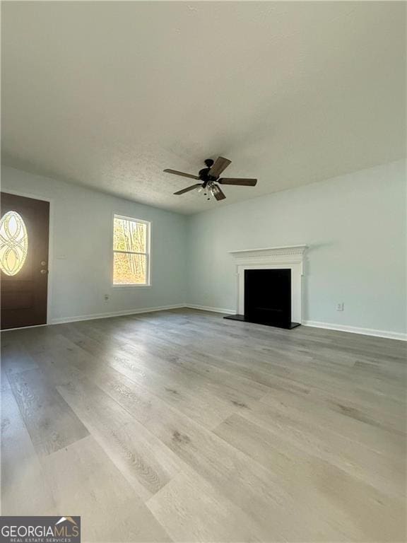 5075 Forest Downs Ln, Atlanta, GA 30349 - unfurnished living room featuring baseboards, a ceiling fan, a fireplace with raised hearth, and wood finished floors