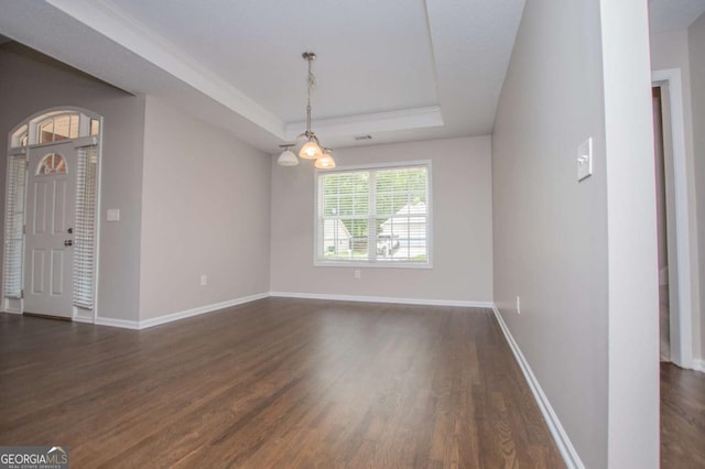empty room with baseboards, a raised ceiling, ornamental molding, and dark wood-style floors