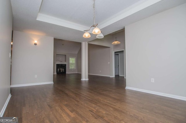 unfurnished living room with baseboards, a raised ceiling, crown molding, and dark wood-style floors