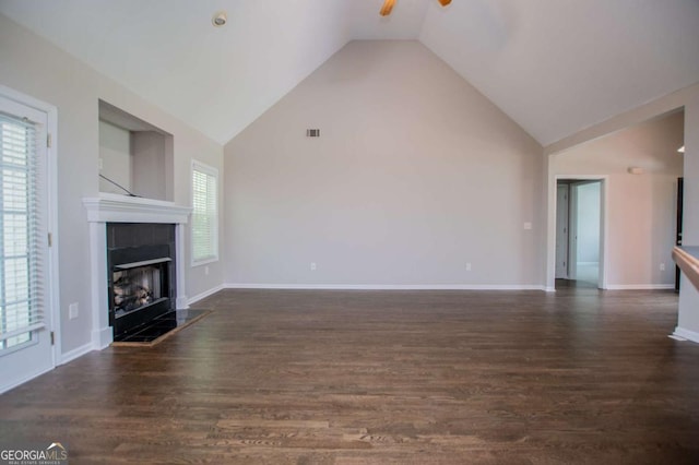 unfurnished living room featuring ceiling fan, plenty of natural light, a tiled fireplace, and wood finished floors