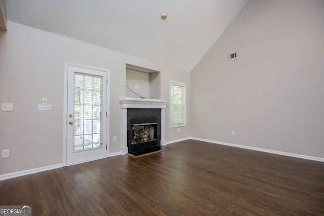 unfurnished living room featuring a tiled fireplace, baseboards, visible vents, and wood finished floors