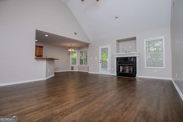 unfurnished living room featuring an inviting chandelier, baseboards, dark wood-type flooring, and a tiled fireplace