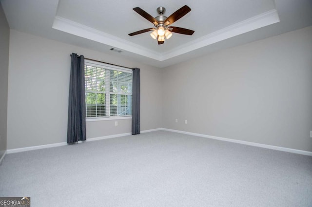spare room with carpet flooring, crown molding, visible vents, and a raised ceiling