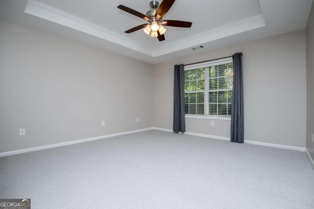 carpeted empty room featuring baseboards, ceiling fan, a tray ceiling, and crown molding