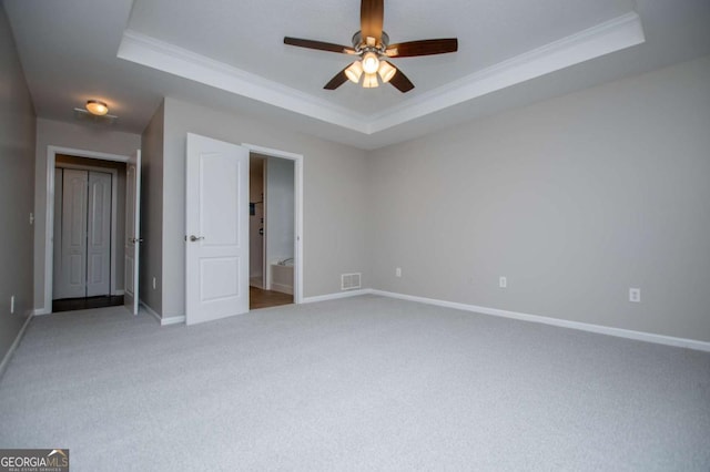 unfurnished bedroom with carpet flooring, visible vents, baseboards, a raised ceiling, and ornamental molding