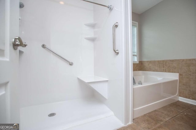 bathroom with walk in shower, a garden tub, tile walls, and tile patterned flooring