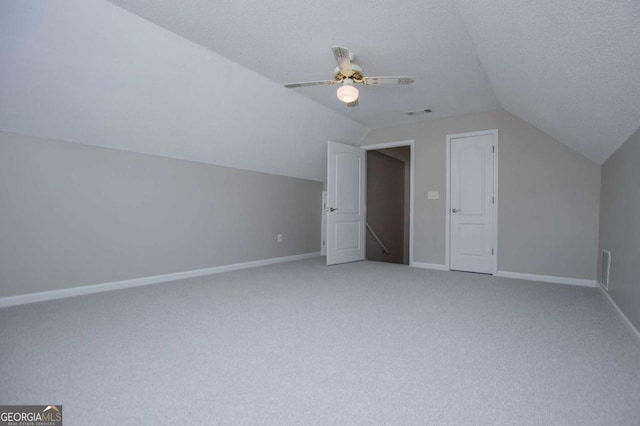 additional living space with light colored carpet, vaulted ceiling, baseboards, and a ceiling fan