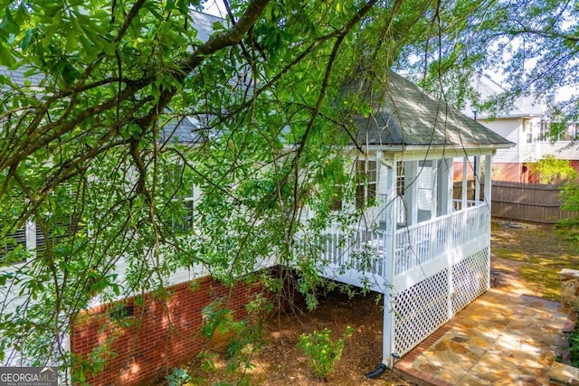 view of property exterior with a shingled roof and fence