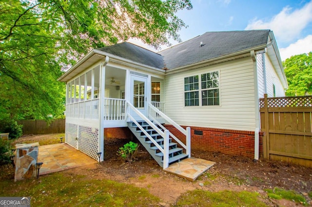rear view of house with fence, stairway, a ceiling fan, a sunroom, and a shingled roof