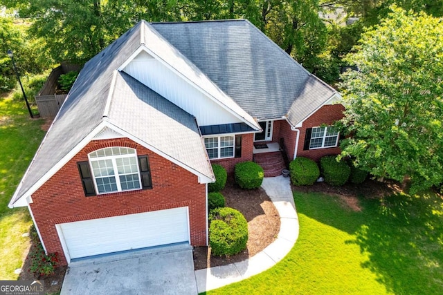 traditional-style home with concrete driveway, a garage, a front lawn, and brick siding