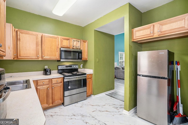 kitchen with stainless steel appliances, a sink, light marble finish floors, light countertops, and baseboards