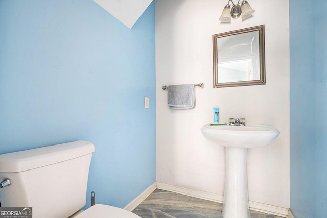 half bath featuring toilet and baseboards