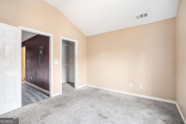 unfurnished bedroom with carpet, vaulted ceiling, a walk in closet, baseboards, and a closet