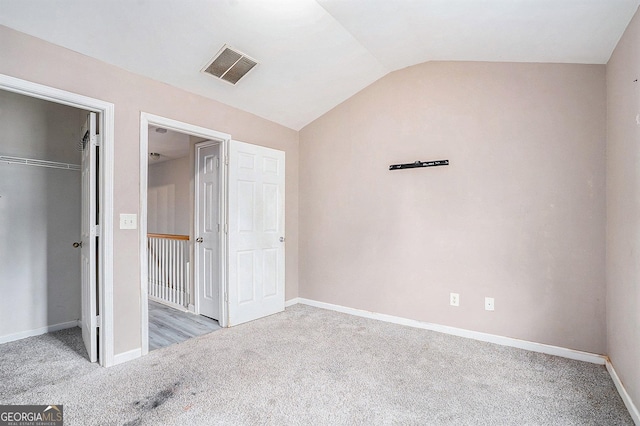 unfurnished bedroom with vaulted ceiling, carpet floors, baseboards, and a closet