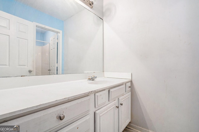 bathroom with vanity, baseboards, and a shower