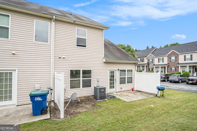 back of house featuring a lawn, central AC, and a shingled roof