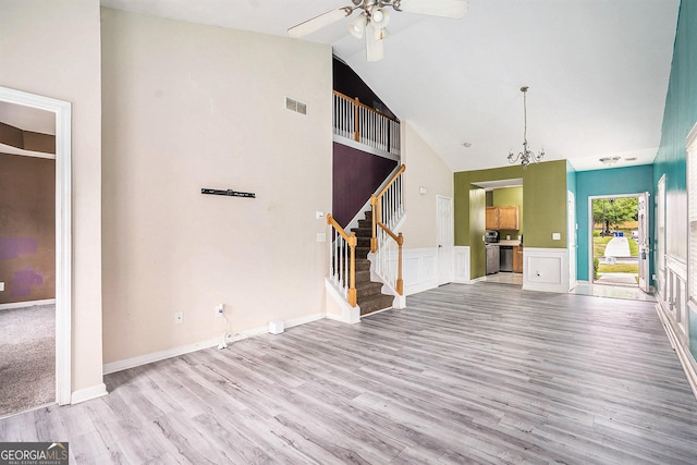unfurnished living room featuring light wood-style flooring, stairs, ceiling fan, high vaulted ceiling, and a chandelier