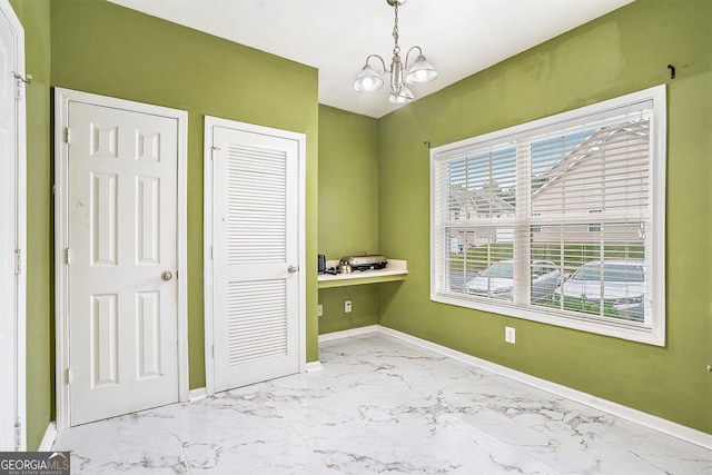 unfurnished bedroom featuring a chandelier, baseboards, marble look tile flooring, a closet, and an office area