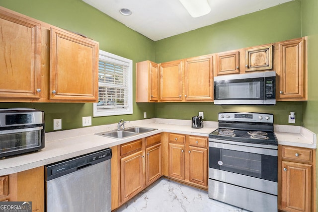 kitchen with appliances with stainless steel finishes, a sink, light marble finish flooring, and light countertops