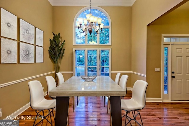 dining area featuring ornamental molding, a notable chandelier, baseboards, and wood finished floors