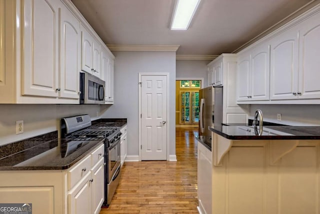 kitchen featuring crown molding, light wood-type flooring, stainless steel appliances, and white cabinetry
