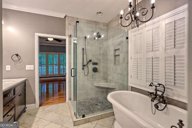 bathroom featuring a stall shower, crown molding, tile patterned flooring, a freestanding tub, and vanity