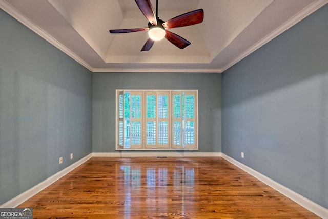 spare room featuring a ceiling fan, a tray ceiling, crown molding, and wood finished floors