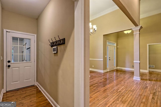 interior space featuring decorative columns, hardwood / wood-style floors, crown molding, visible vents, and baseboards