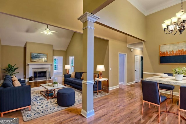 living room featuring ceiling fan with notable chandelier, a towering ceiling, baseboards, and wood finished floors
