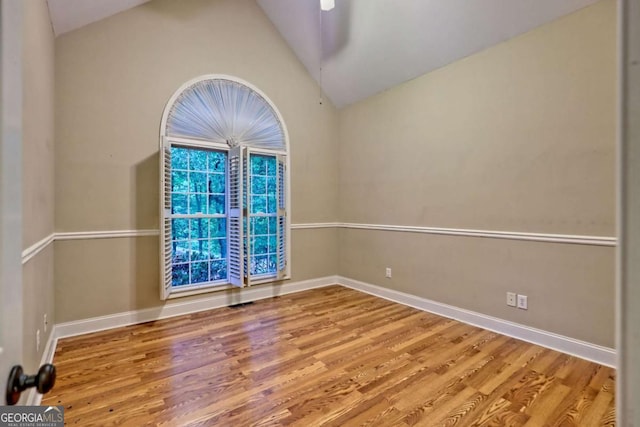 empty room with lofted ceiling, baseboards, and wood finished floors