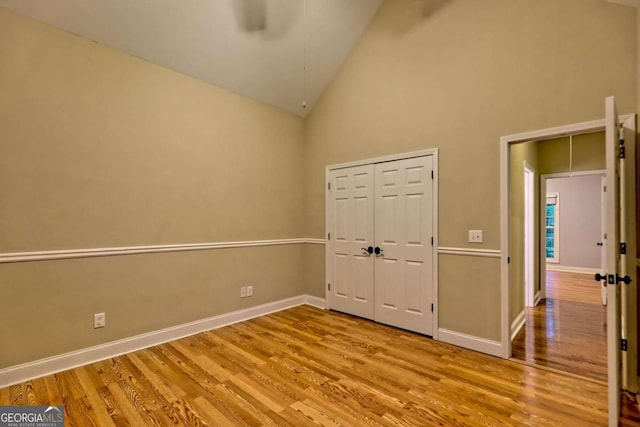 unfurnished room with baseboards, ceiling fan, high vaulted ceiling, and wood finished floors