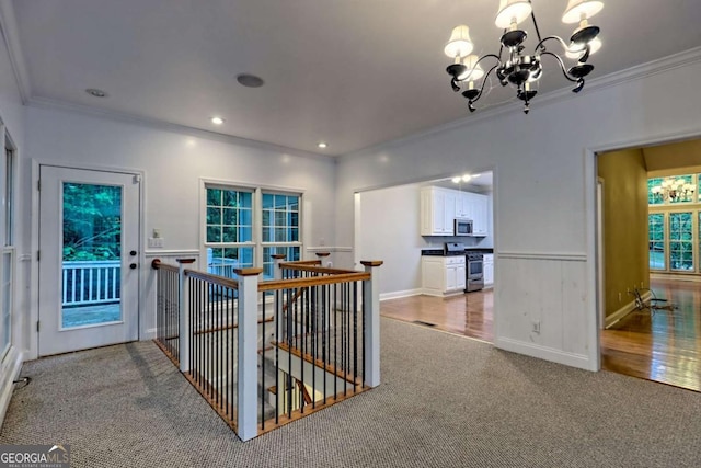 hallway featuring a notable chandelier, ornamental molding, an upstairs landing, and carpet