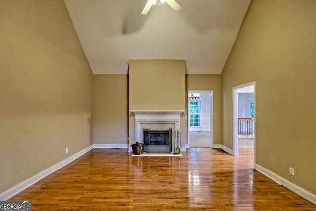 unfurnished living room featuring ceiling fan, baseboards, a fireplace with flush hearth, and wood finished floors