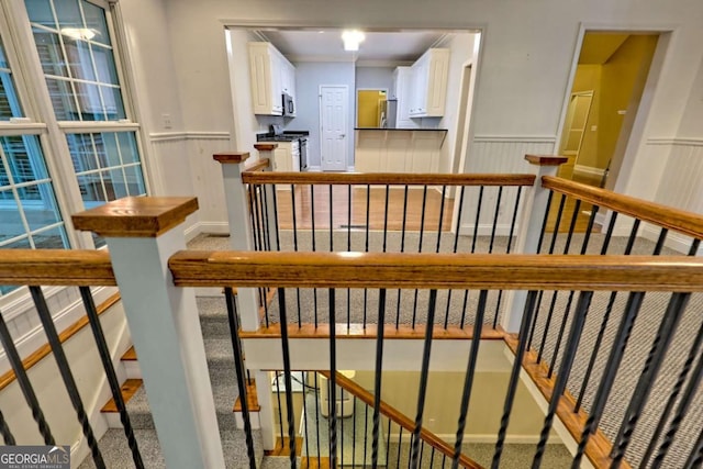 staircase featuring wainscoting and carpet flooring