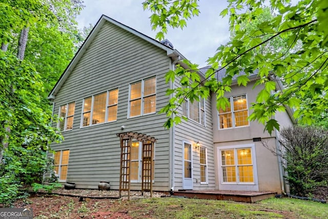 rear view of house featuring stucco siding