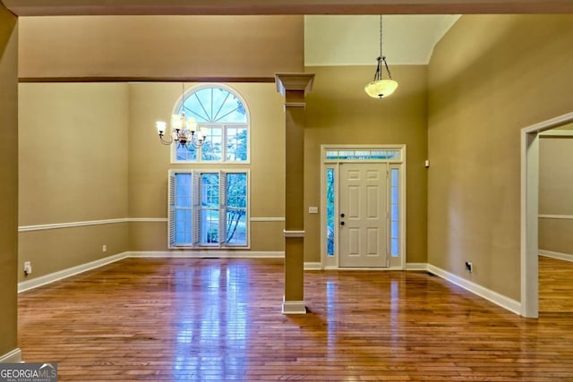 entrance foyer featuring an inviting chandelier, hardwood / wood-style flooring, baseboards, and high vaulted ceiling