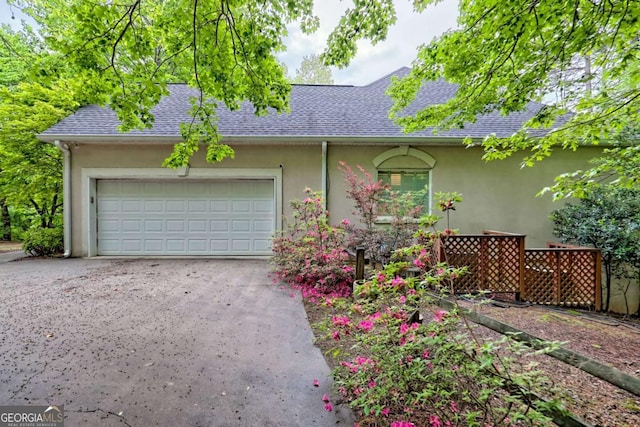 ranch-style house with stucco siding, roof with shingles, and a garage