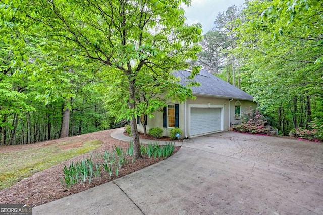 view of side of home featuring roof with shingles, an attached garage, stucco siding, and driveway