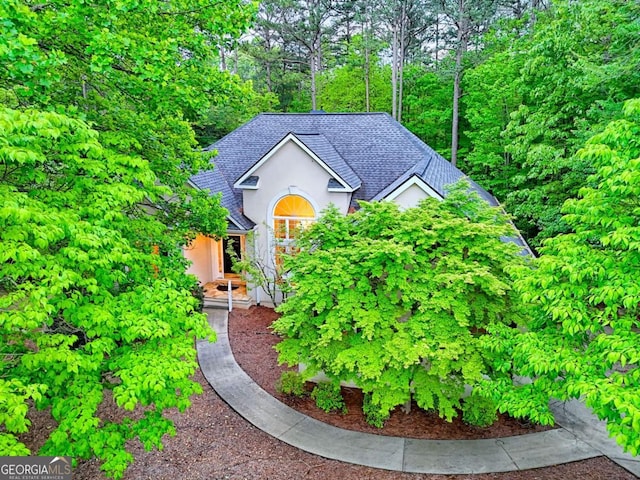 view of front of property featuring stucco siding and roof with shingles