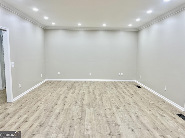 spare room with baseboards, light wood finished floors, crown molding, and visible vents