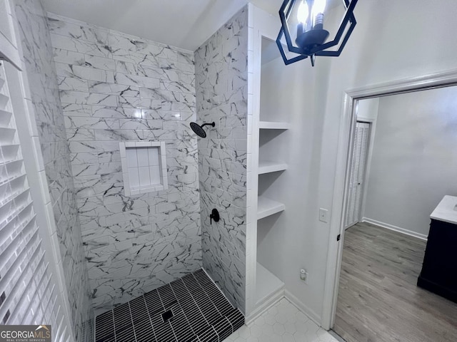 full bathroom featuring a tile shower, vanity, and wood finished floors