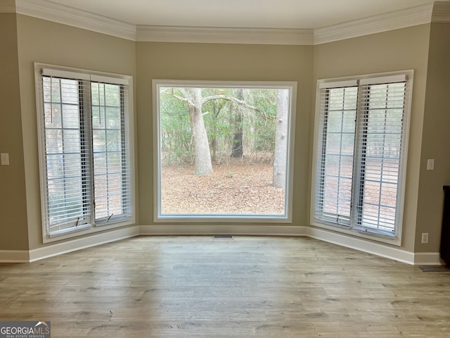 unfurnished dining area with baseboards, crown molding, and wood finished floors