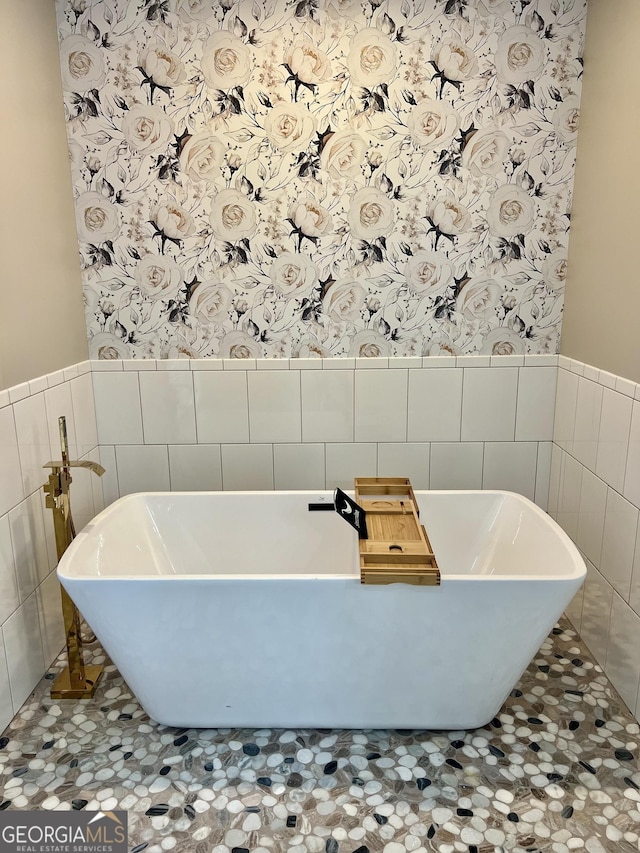 full bathroom with tile walls, a wainscoted wall, and a freestanding tub