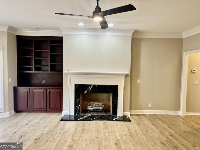 unfurnished living room with a ceiling fan, baseboards, a high end fireplace, crown molding, and wood finished floors