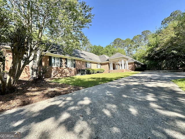 view of front facade with driveway, brick siding, and a front yard
