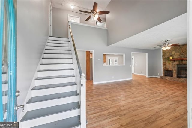 3880 Dial Mill Rd NE, Conyers, GA 30013 - stairway with ceiling fan, wood finished floors, baseboards, and a stone fireplace