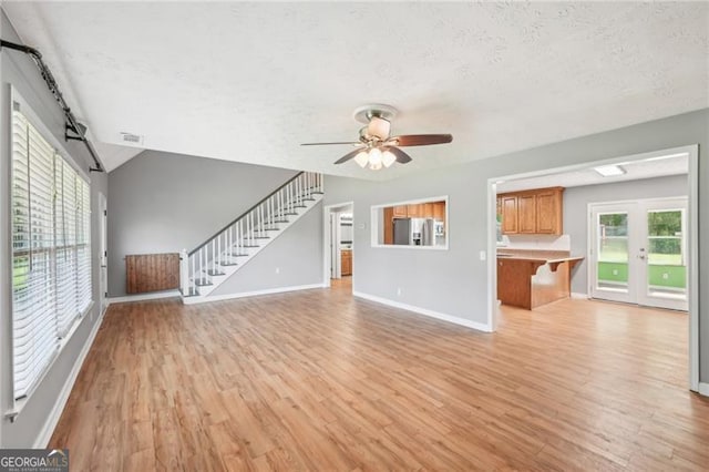 3880 Dial Mill Rd NE, Conyers, GA 30013 - unfurnished living room with a textured ceiling, light wood-style floors, a ceiling fan, baseboards, and stairs