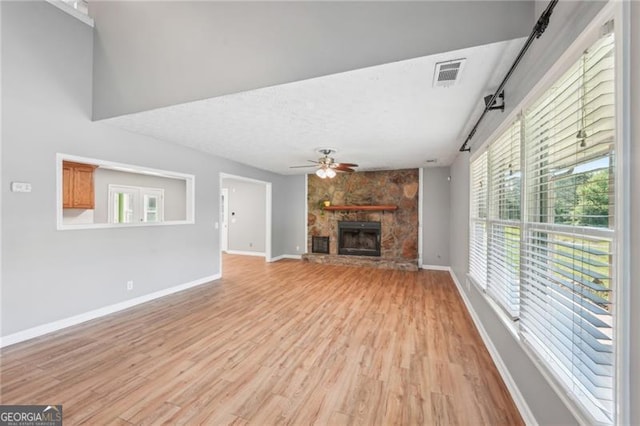 3880 Dial Mill Rd NE, Conyers, GA 30013 - unfurnished living room featuring light wood-style flooring, baseboards, a ceiling fan, and a stone fireplace