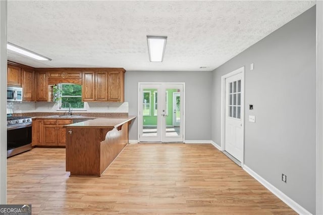 3880 Dial Mill Rd NE, Conyers, GA 30013 - kitchen with appliances with stainless steel finishes, a sink, a peninsula, french doors, and brown cabinetry